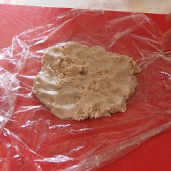 手順8：6で使ったラップに生地をスプーンですくって広げる。約大さじ1の餡をのせ、ラップで茶巾絞りのように包む（具は多少余る）。ベーキングシートの上にのせる。