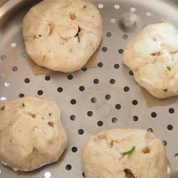 手順9：蒸し器の上に間隔を開けて置く。ラップをまんじゅうにかぶせ、暖かい所で膨らむまで置く（10分位）。並べ切らない場合は油を塗った皿などに並べておく。